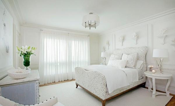 Для белой спальни прекрасно подойдет массивная кровать, небольшой туалетный столик и красивые элементы декора